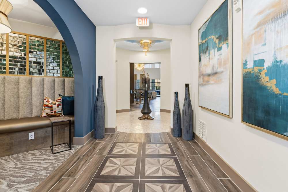 Hallway with decorative art and view of clubhouse at The Heyward Apartments in Corinth, Texas.