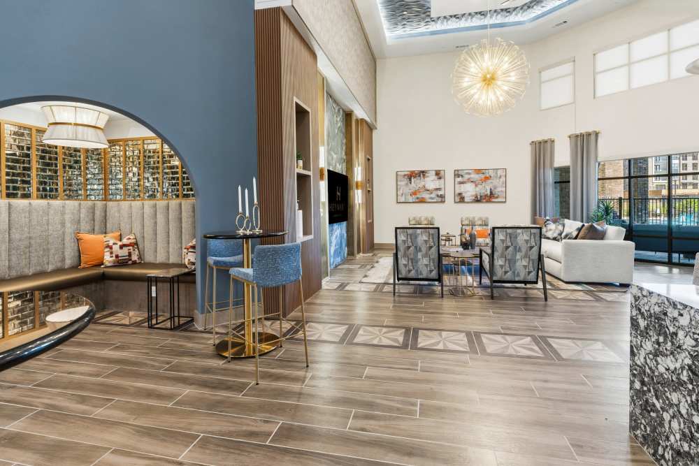 Clubhouse lounge with modern seating and chandelier at The Heyward Apartments in Corinth, Texas.