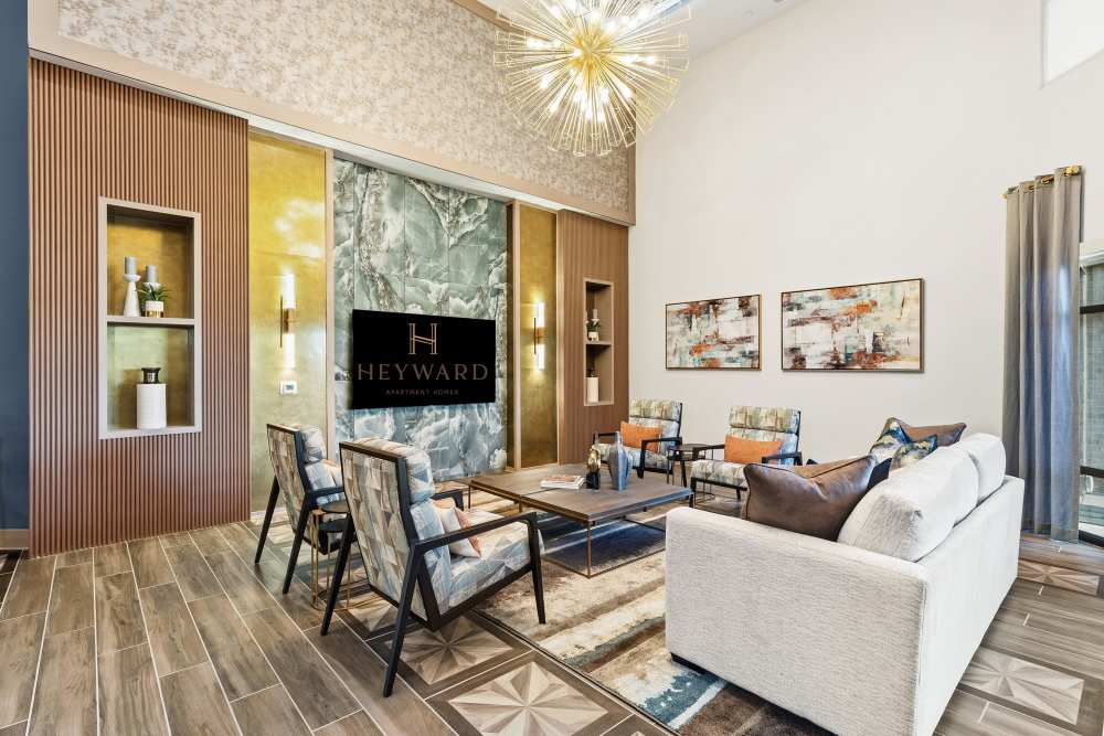 Clubhouse lounge with modern decor and large chandelier at The Heyward Apartments in Corinth, Texas.
