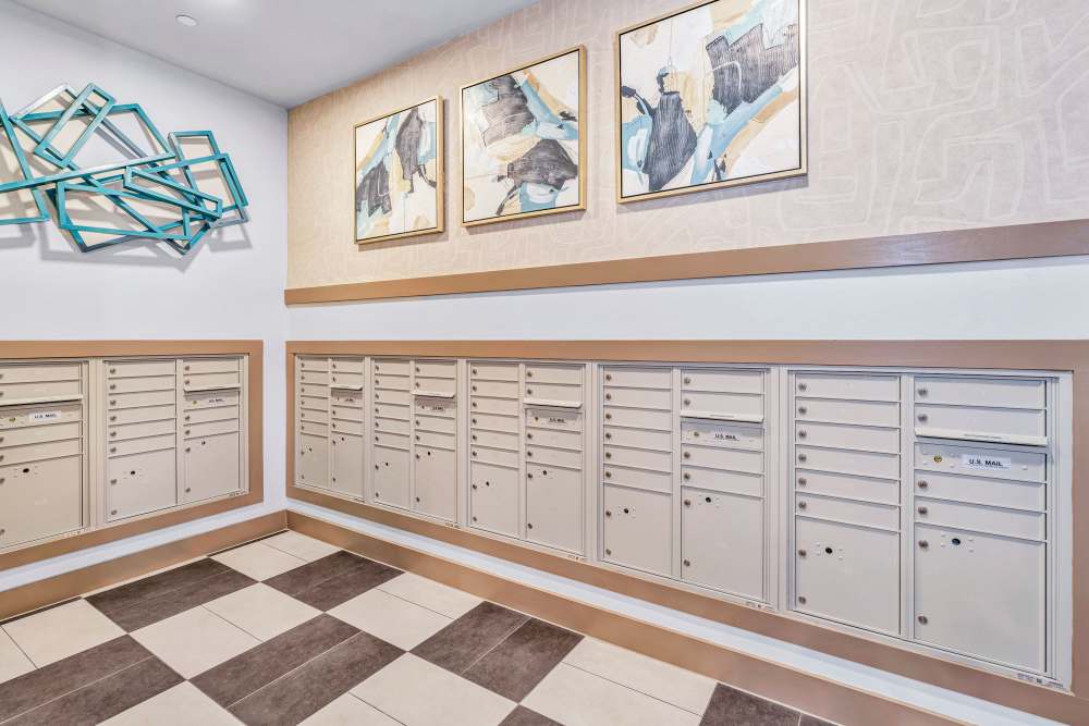 Mailroom with wall-mounted mailboxes and modern artwork at The Heyward Apartments in Corinth, Texas.