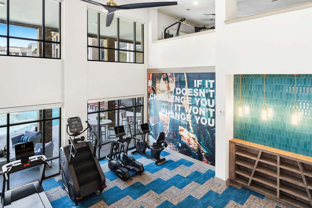 Workout area with cardio machines and teal accent wall at The Heyward Apartments in Corinth, Texas.