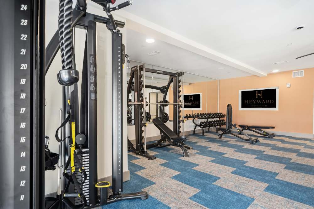 Strength training area with cable machines and free weights at The Heyward Apartments in Corinth, Texas.