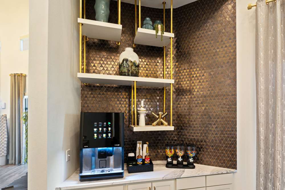 Coffee station with beverage machine and decorative shelving at The Heyward Apartments in Corinth, Texas.