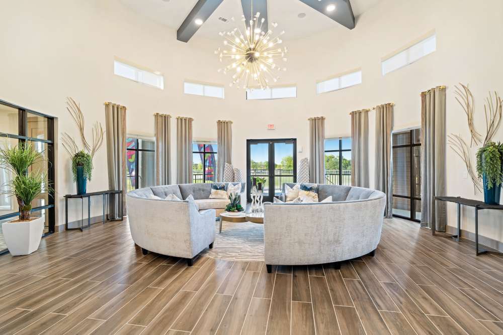 Spacious clubhouse with curved sofas and large windows at The Heyward Apartments in Corinth, Texas.