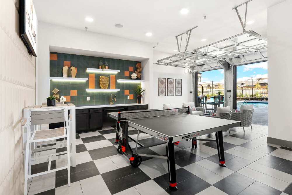 Ping pong table in game room with open view to pool at The Heyward Apartments in Corinth, Texas.