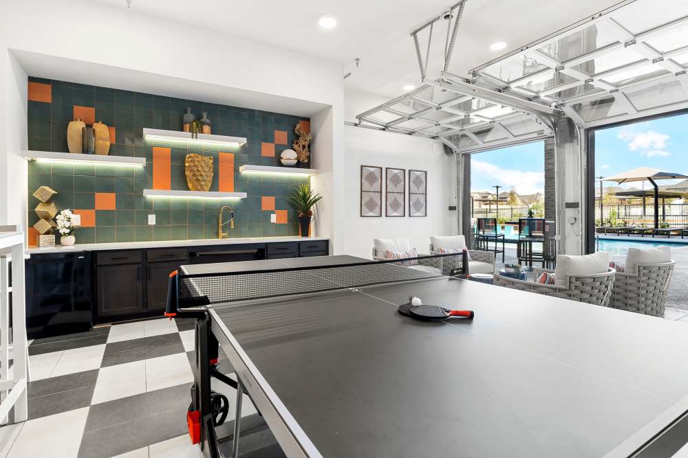 Game room with ping pong table and view of pool at The Heyward Apartments in Corinth, Texas.