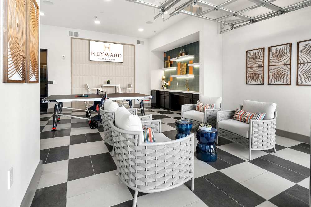 Indoor lounge with ping pong table and Heyward signage at The Heyward Apartments in Corinth, Texas.