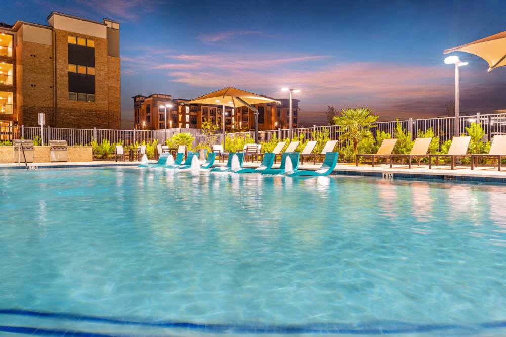 Pool with fountains and sunset view at The Heyward Apartments in Corinth, Texas.