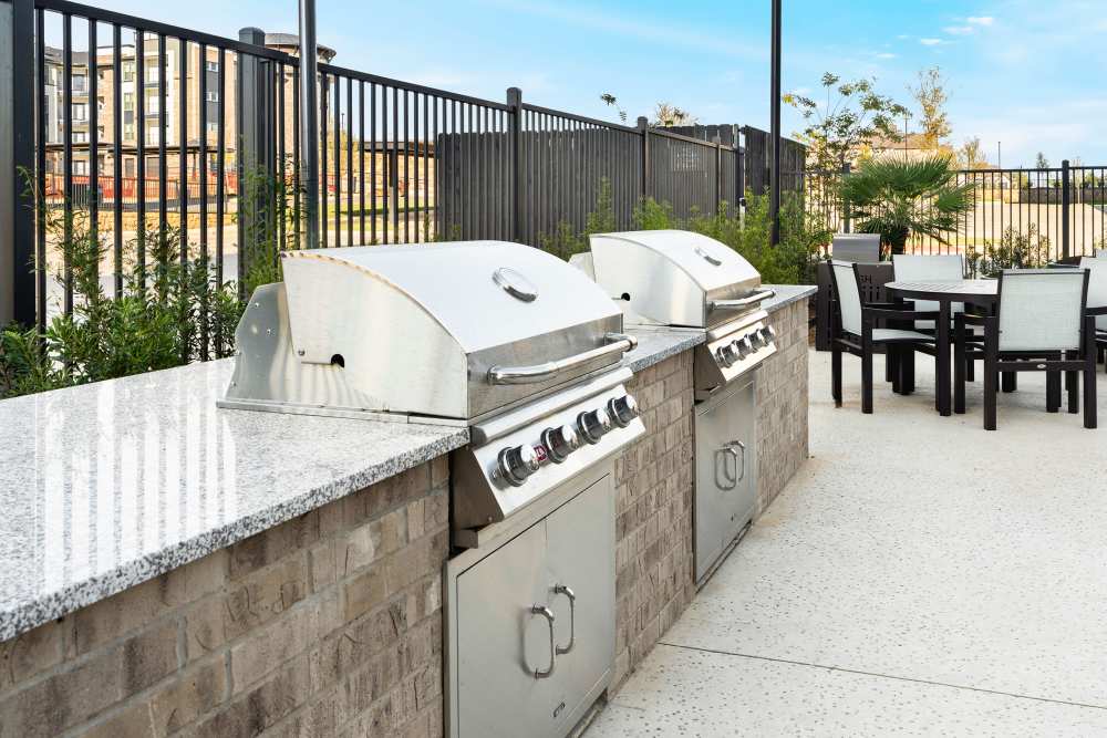 Outdoor grilling station with stainless steel grills at The Heyward Apartments in Corinth, Texas.