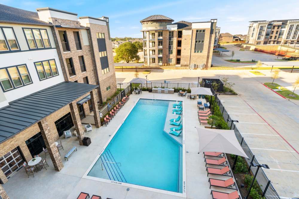 Aerial view of pool with lounge seating at The Heyward Apartments in Corinth, Texas.