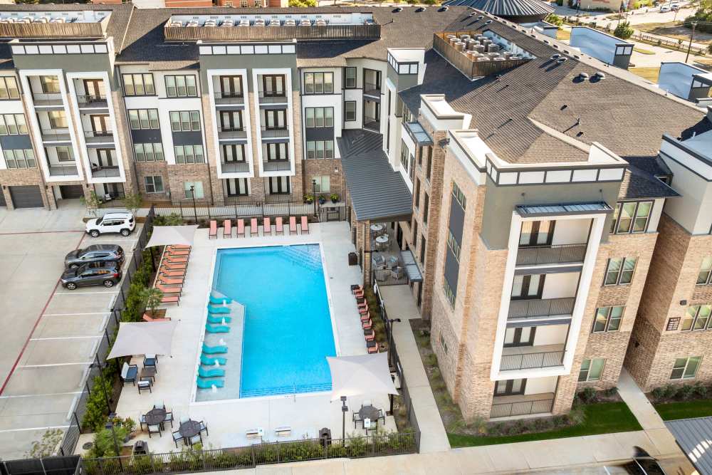 Aerial view of pool and apartment buildings at The Heyward Apartments in Corinth, Texas.