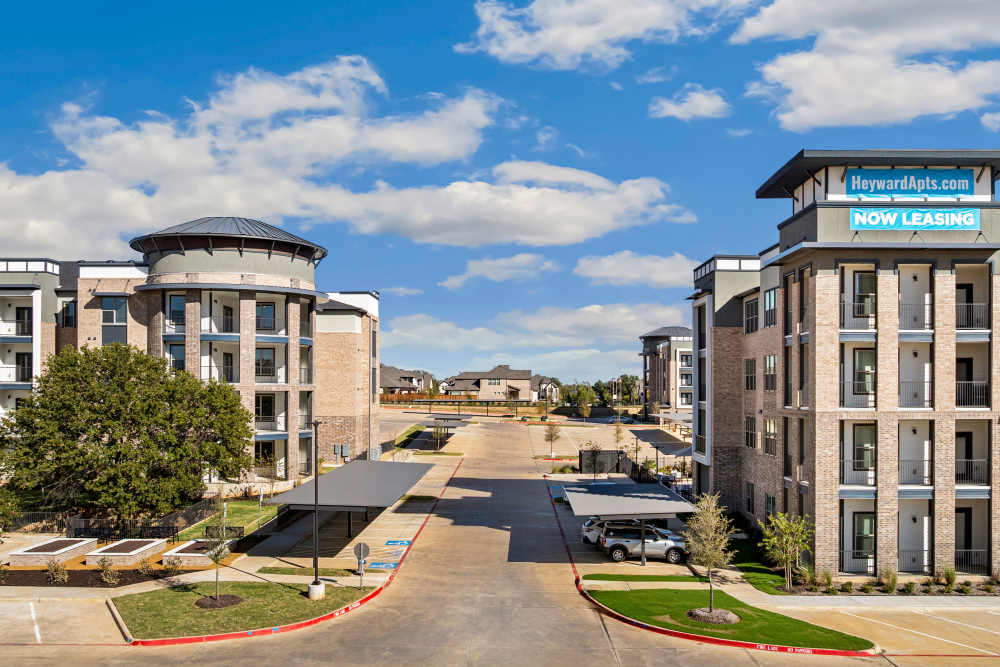 Exterior view of apartment buildings with leasing banner at The Heyward Apartments in Corinth, Texas.