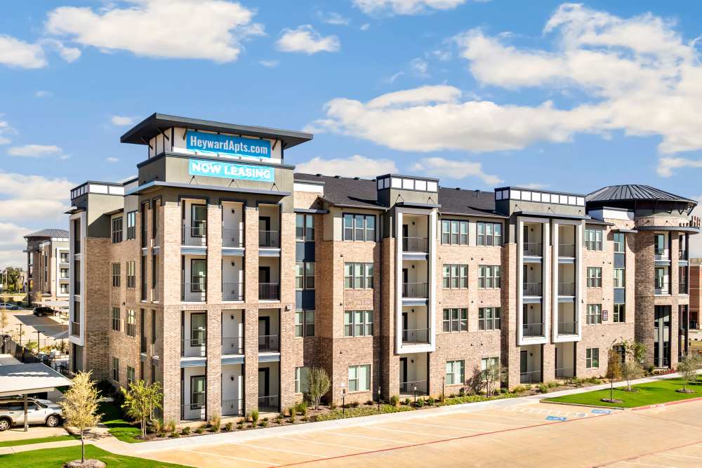 Apartment building exterior with leasing banner at The Heyward Apartments in Corinth, Texas.