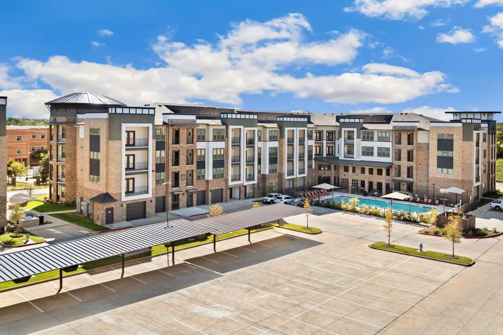 Aerial view of apartment building with pool and parking at The Heyward Apartments in Corinth, Texas.
