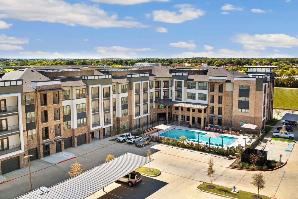Apartment building with pool and covered parking at The Heyward Apartments in Corinth, Texas.