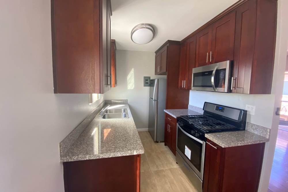 Galley kitchen with stainless steel appliances and wood cabinets at The Indie Glendale Collection in Glendale, California