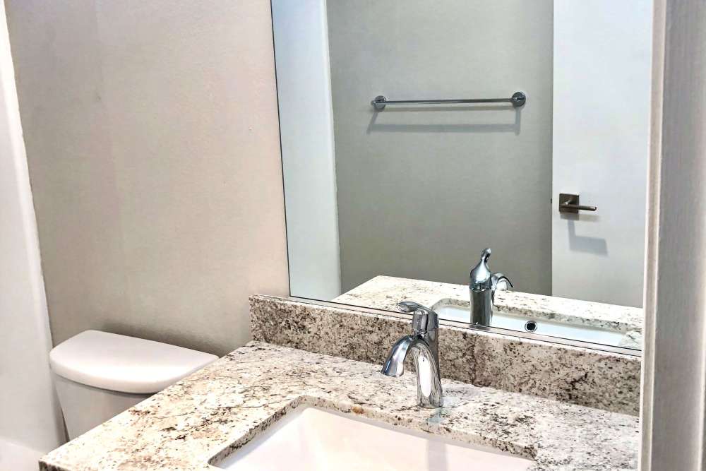 Bathroom vanity with granite countertop and mirror at The Indie Glendale Collection in Glendale, California