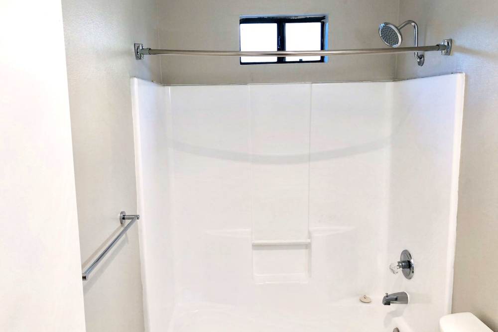 Bathroom with white tub and shower combo at The Indie Glendale Collection in Glendale, California