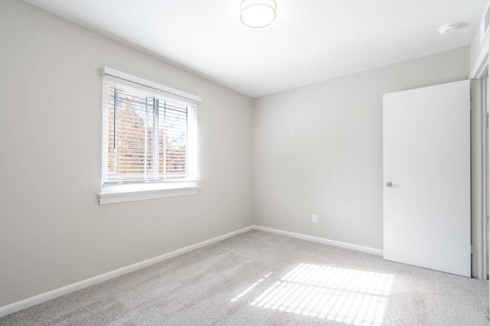 Unfurnished well-lit apartment bedroom featuring windows provided with blinds at Deering Manor in Richmond, Virginia
