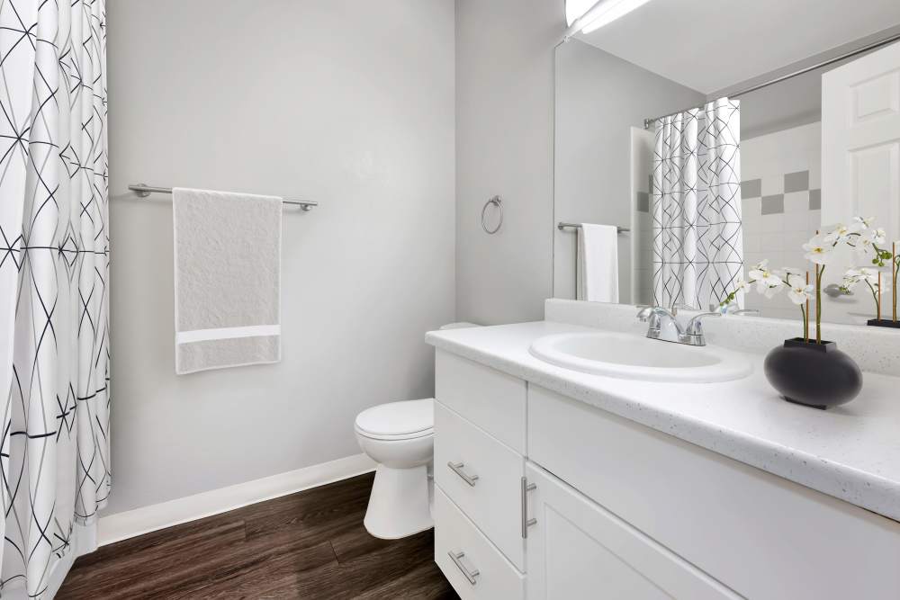 A model bathroom with white cabinets and updated lighting at Westridge Apartments in Aurora, Colorado