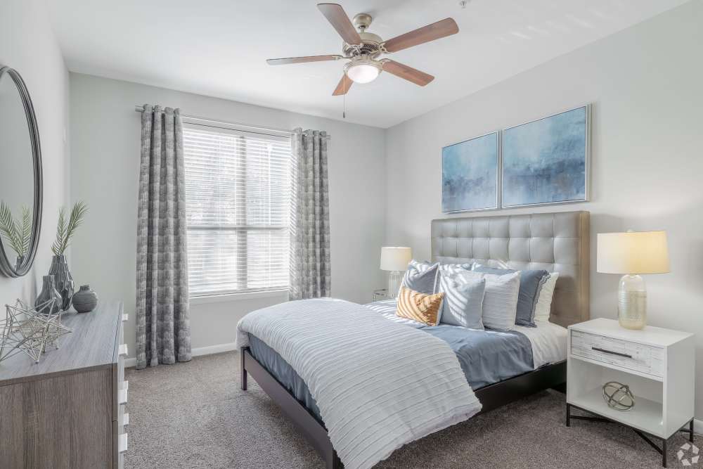 A furnished bedroom with a ceiling fan and large window at South Ridge in Greenville, South Carolina