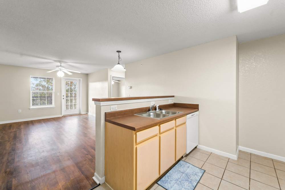 Open kitchen and living area with light wood cabinetry, dark flooring, and natural light at Callaway Village Apartments in Fulton, Missouri