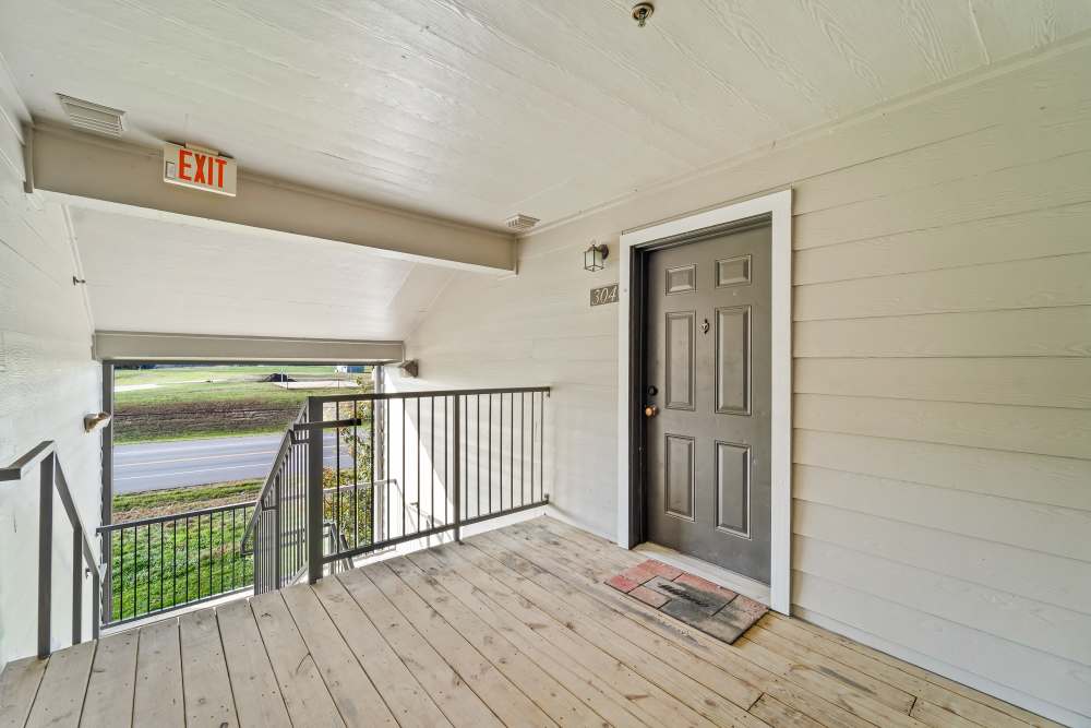 Exterior corridor with wooden flooring and visible exit sign at Callaway Village Apartments in Fulton, Missouri