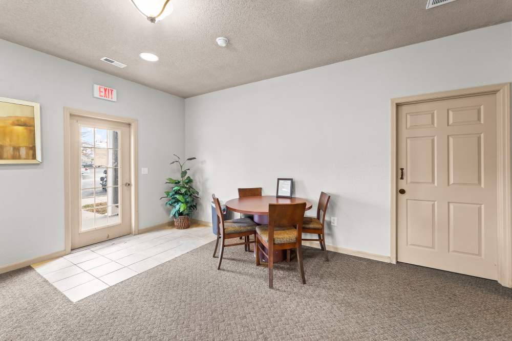 Small, well-lit room with round table, four chairs, and exit door at Callaway Village Apartments in Fulton, Missouri