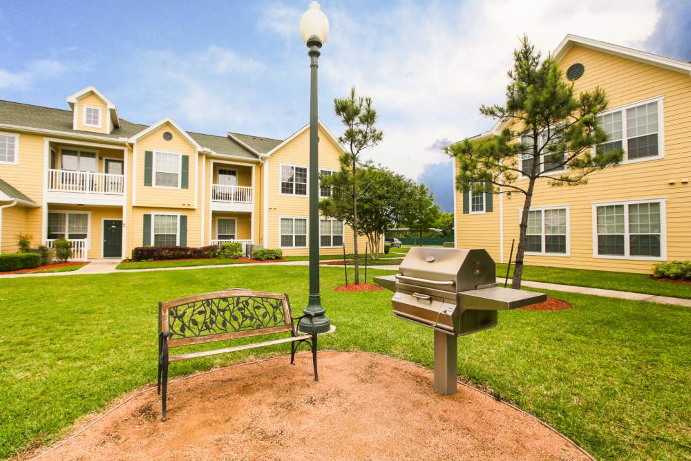 Inviting outdoor space with grill and decorative bench surrounded by greenery at Country Lane in Angleton, Texas