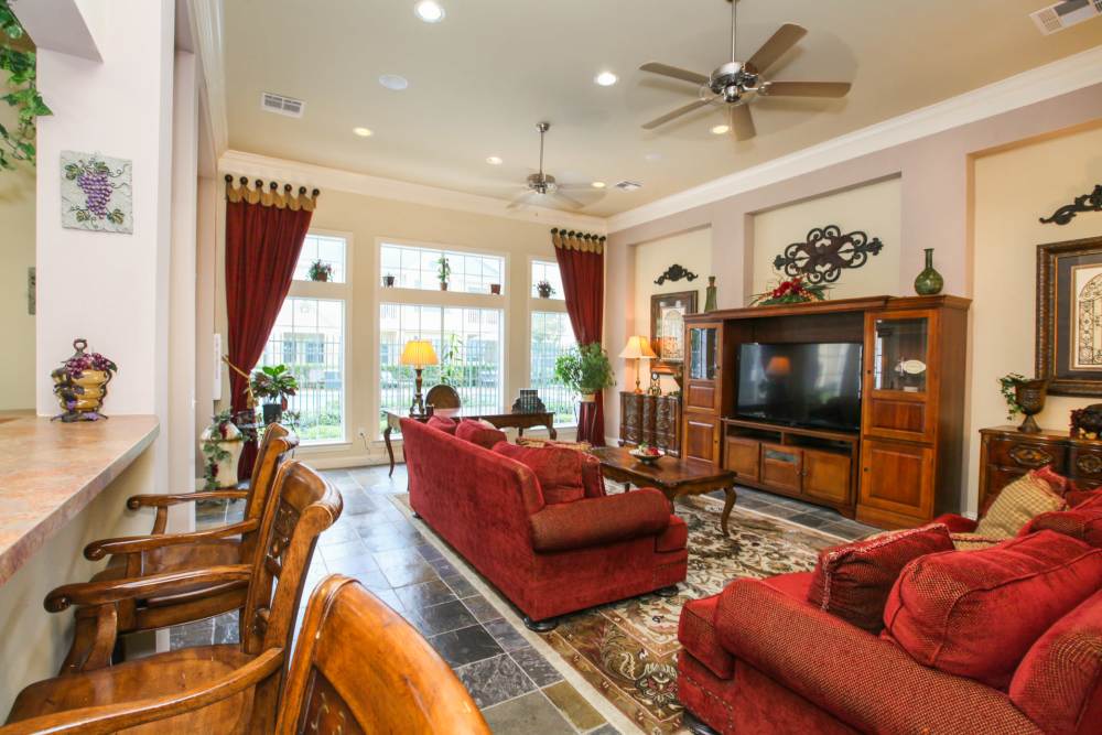 Sunlit living room with plush red sofas and elegant decor at Country Lane in Angleton, Texas