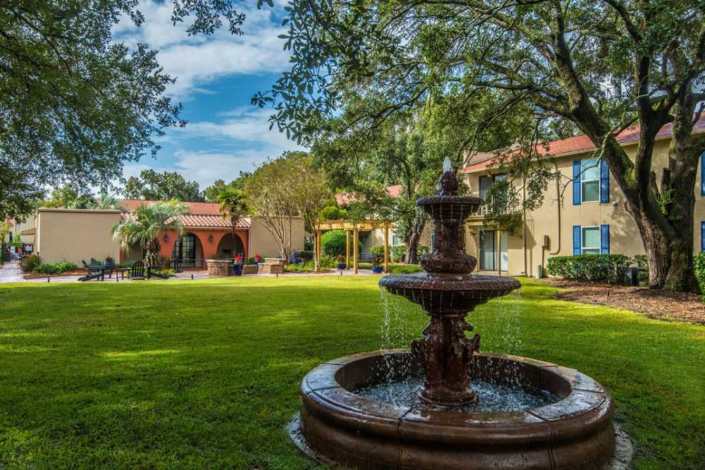 Fountain in green courtyard with trees and buildings at Spanish Oaks in Charleston, South Carolina