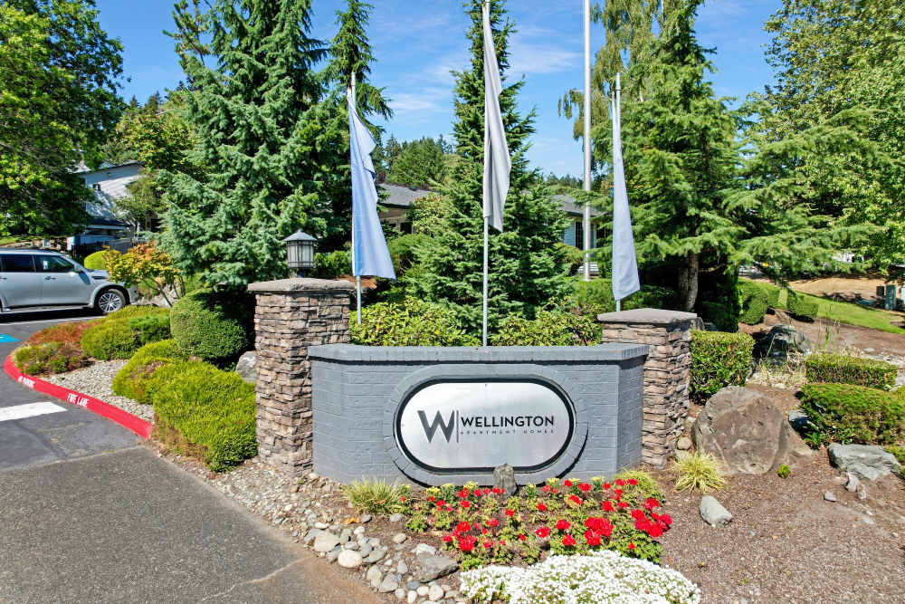 The monument sign and flags at the entrance of Wellington Apartments in Silverdale, Washington