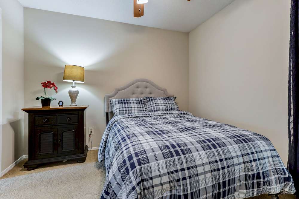Cozy bedroom with plaid bedding and lamp at Spanish Oaks in Charleston, South Carolina