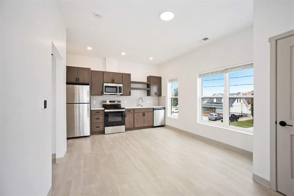Modern kitchen with stainless steel appliances, wood cabinets, and large windows at Terra Station, Hudsonville, Michigan
