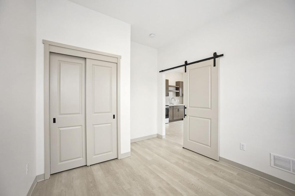 Light-filled room with sliding closet doors and barn door leading to kitchen at Terra Station, Hudsonville, Michigan