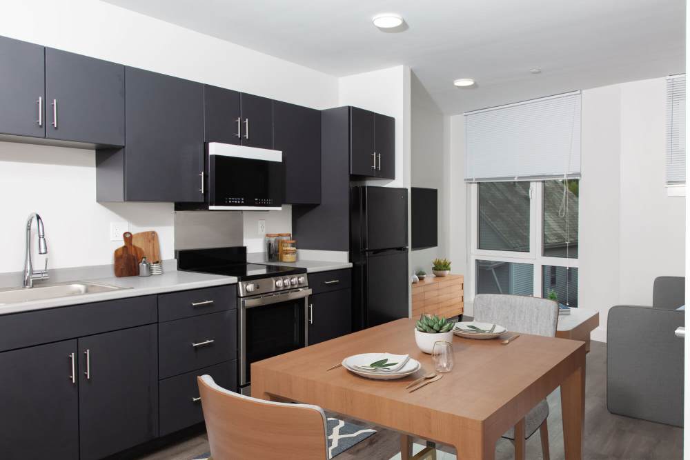 Full equipped kitchen with black cabinets and dining table at The Lighthouses in Salem, Massachusetts