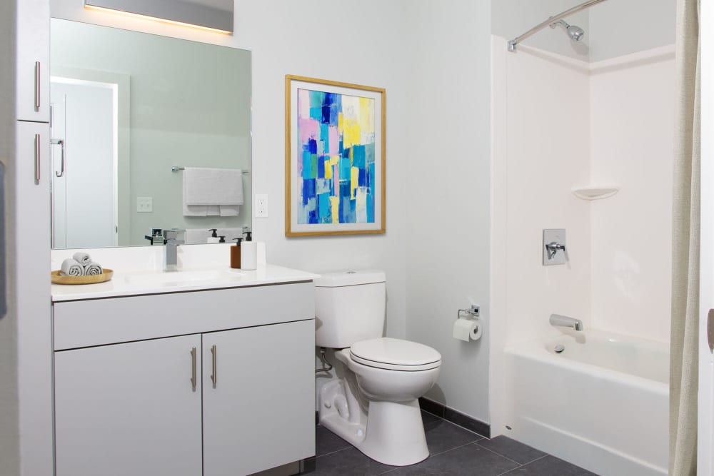 Modern bathroom with white fixtures, striped shower curtain, and abstract wall art at The Lighthouses in Salem, Massachusetts