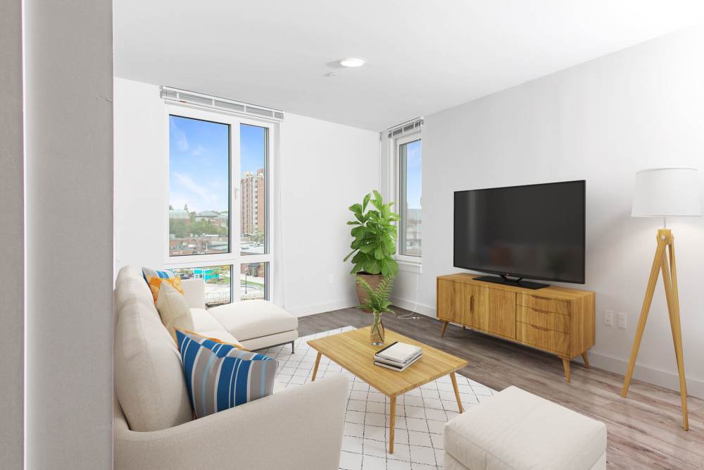 Contemporary living room with sectional sofa, wooden furniture, large windows, and urban view at The Lighthouses in Salem, Massachusetts