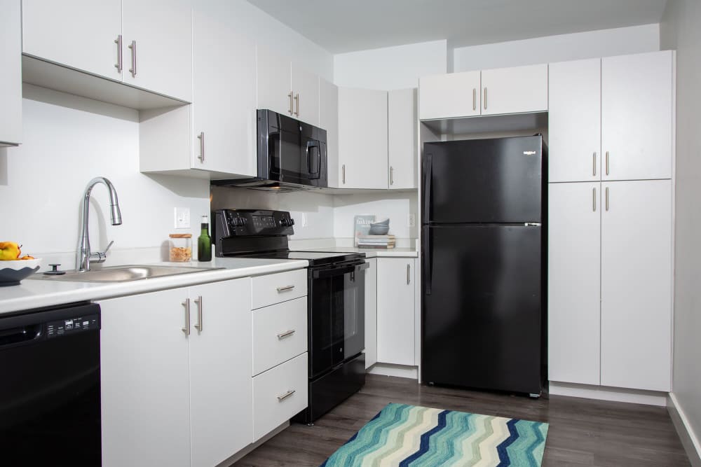 Full equipped kitchen with white cabinets black appliances at The Lighthouses in Salem, Massachusetts