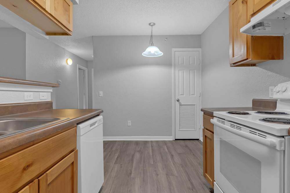Open kitchen with white appliances and granite countertop at Garden Courtyards in Tulsa, Oklahoma