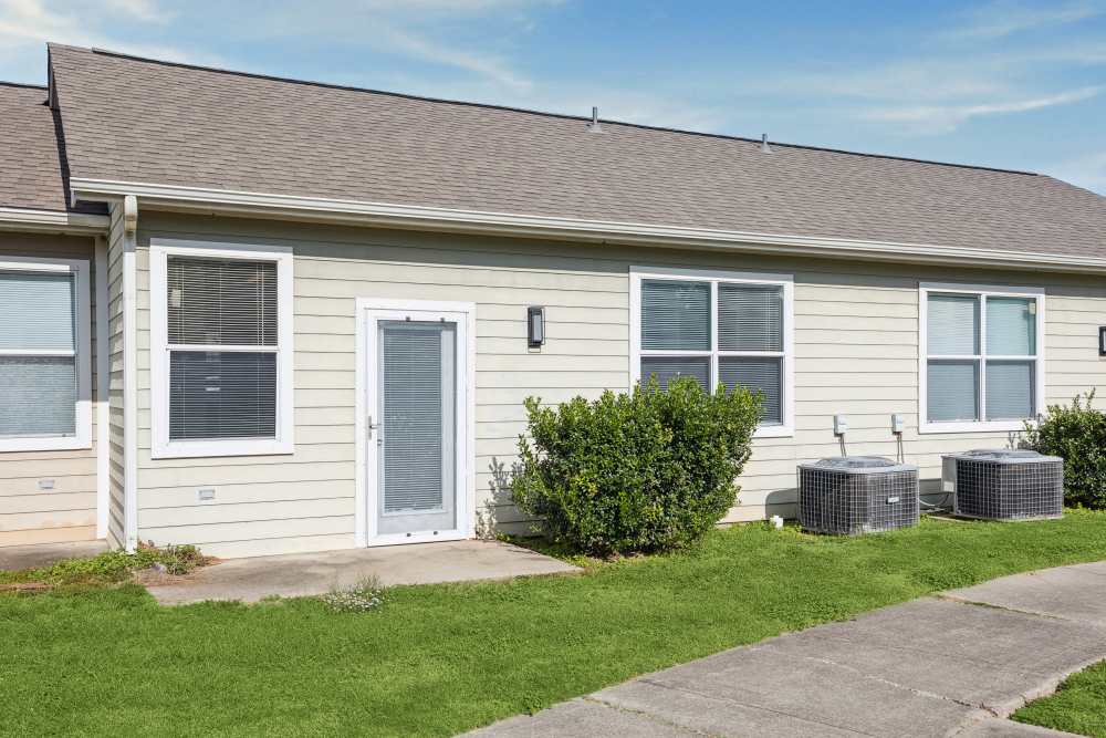 Charming exterior with lush greenery and modern air conditioning units at Gibraltar Senior in Clute, Texas