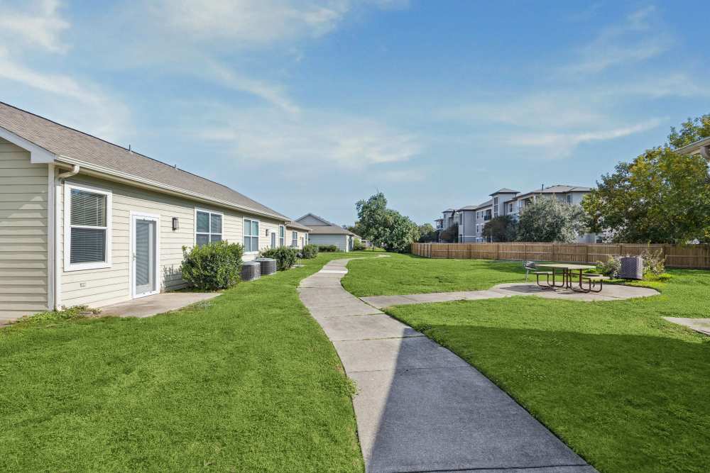 Lush green walkway with apartment access and picnic area at Gibraltar Senior in Clute, Texas