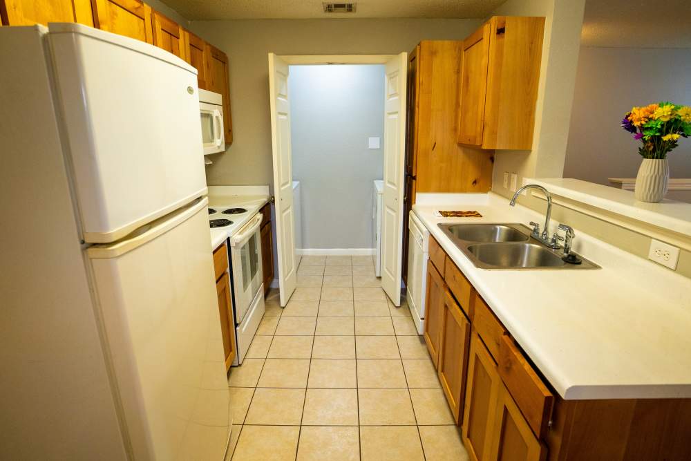 Kitchen with white appliances, tile flooring and raised countertop at Hampton Village in Palestine, Texas