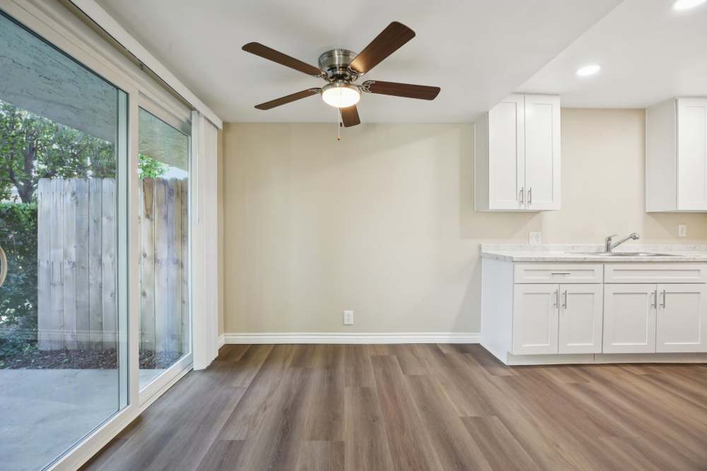 Open layout carpeted living room with plenty of room for a couch, coffee table, and more with entry to patio at North Pointe Villas in La Habra, California