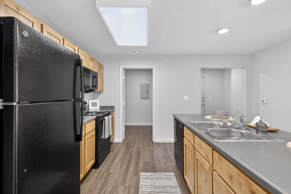 Kitchen with black appliances and hard wood flooring at Juniper Pointe in Kaufman, Texas