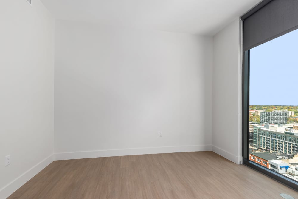 Empty bedroom with wood flooring and partial city view through tall window at Studio Park Tower & Lofts in Grand Rapids, Michigan