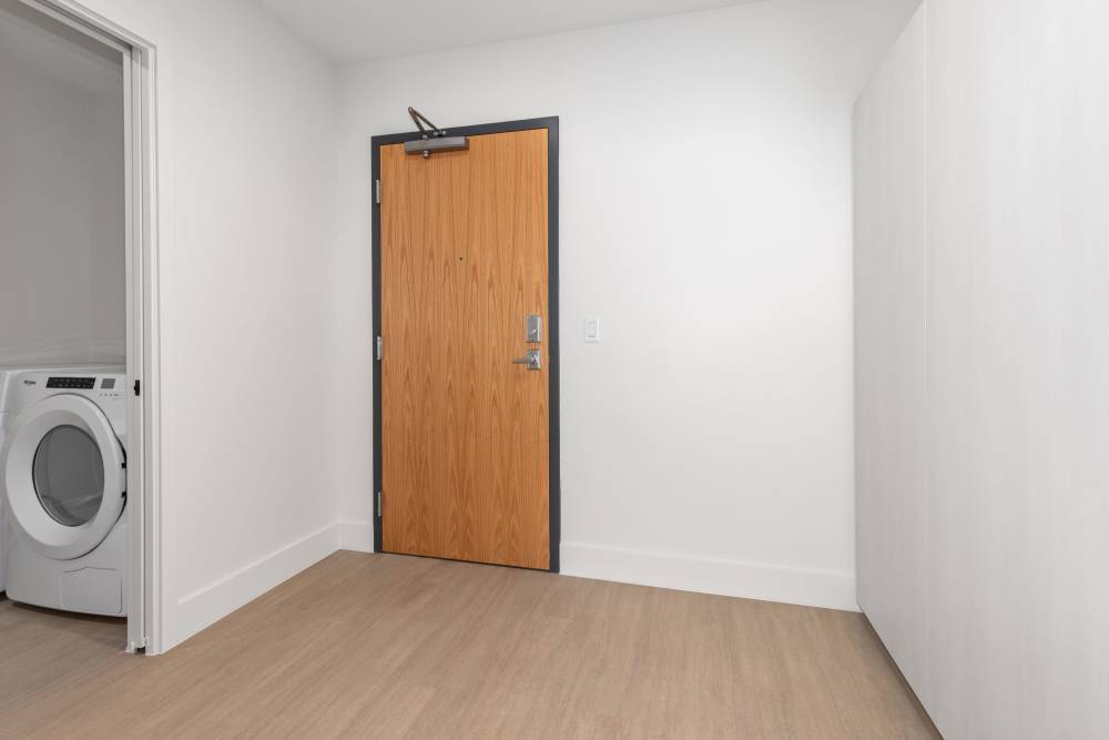 Entryway with wood door and adjacent laundry space at Studio Park Tower & Lofts in Grand Rapids, Michigan