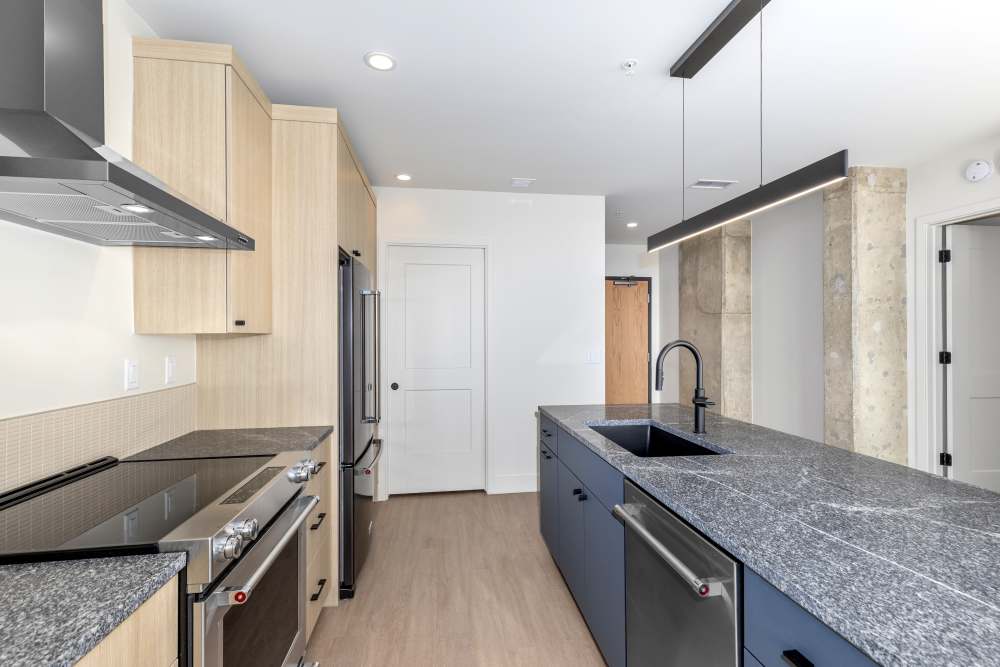 Modern kitchen with granite island and wood cabinets at Studio Park Tower & Lofts in Grand Rapids, Michigan
