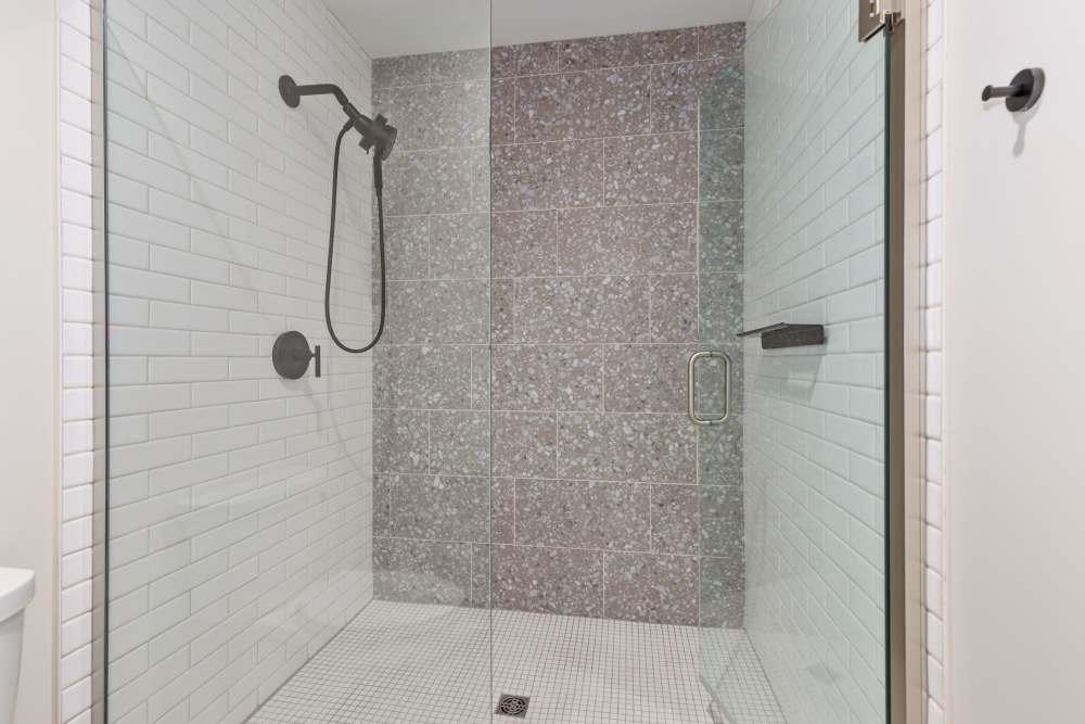 Walk‑in shower with tile walls and glass door at Studio Park Tower & Lofts in Grand Rapids, Michigan
