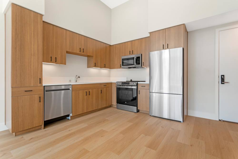 Kitchen and Dining/Living Room at The Millton with wood style plank flooring and stainless steel appliances.
